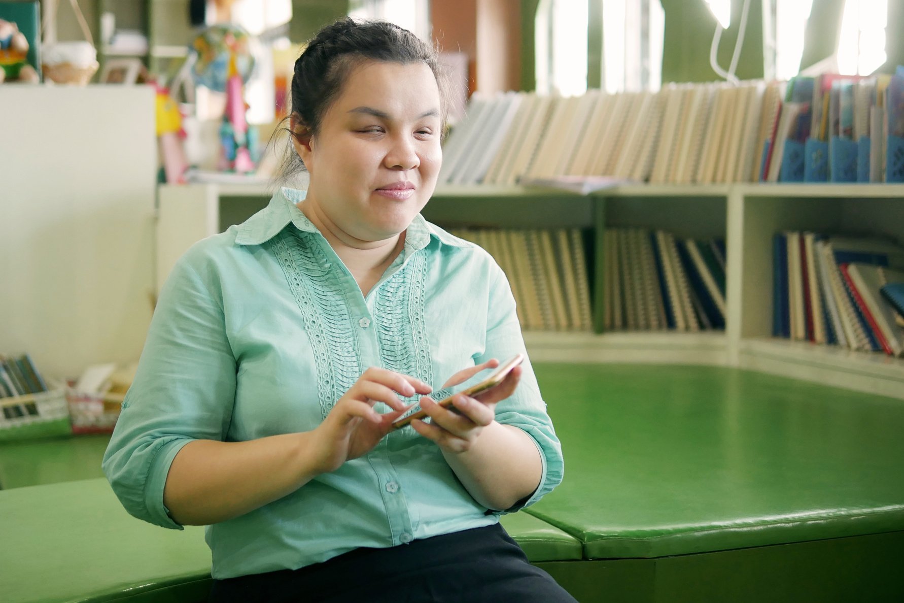 Asian young blind person woman using smart phone with voice accessibility for persons with disabilities in creative workplace.